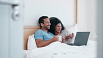 Laptop, tea and laughing with a couple in bed together in the morning to relax in their home. Computer, coffee or app with a man and woman watching a video or movie in the bedroom of their apartment