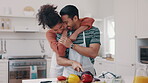 Hug, food and a couple cooking in the kitchen of their home together for a romantic meal on their anniversary. Love, health or nutrition with a happy man and woman preparing vegetables in a house