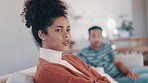 Conflict, sad and woman on a sofa in an argument with her boyfriend for break up, cheating or toxic relationship. Moody, upset and young female person fighting with her partner in living room at home