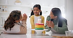 Applause, family singing happy birthday to a girl and a senior woman with her daughter in the kitchen of a home. Cake, party or celebration with a grandmother, mother and girl clapping in excitement
