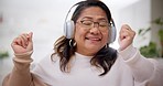 Headphones, dance and mature woman in the living room listening to music, radio or playlist. Energy, smile and happy Asian female person moving and streaming a song or album in the lounge of her home