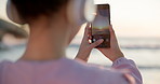 Phone, sunset and photograph with a woman at the beach for freedom, travel or vacation in the morning. Nature, summer and social media with a young female tourist by the ocean for a profile picture