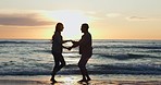 Silhouette, dance and a couple at the beach during sunset for bonding, happiness and love on a date. Smile, dark and a playful man and woman at the ocean or sea for fun on a vacation in summer