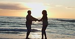 Happy, sunset and silhouette of couple at beach for relax, summer vacation and travel. Love, adventure and wellness with man and woman on seaside date for holiday, marriage and holding hands together