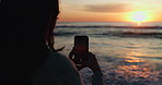 Sunset, photographer and phone with person at beach for social media, relax or vacation. Silhouette, ocean and travel blog with woman and picture on holiday for website, live streaming and influencer