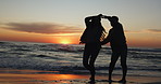 Sunset, dancing and couple on a beach for vacation or tropical holiday together for love or care on island. Silhouette, man and woman with happiness on anniversary with travel freedom at ocean