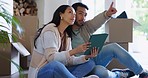 Couple, pointing and tablet in new house, floor and planning together with thinking, idea or fresh start in living room. Man, woman and chat by boxes, cardboard package or moving at apartment lounge