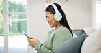 Woman, sofa and headphones with phone for music streaming service, social media and network at home. Person or online user scroll internet or website with audio, electronics and mobile subscription 
