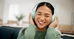 Headphones, dance and young woman in the living room singing to music, radio or playlist at home. Happy, smile and young Asian female person listening to song or album on a sofa in her apartment.