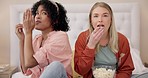 Horror, television and women friends with popcorn on bed for scary, movie or serial killer documentary at home. Watching tv, face and ladies in bedroom with terror, film or video, snack and streaming