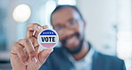 Hand, vote and badge with a black man in government for support or motivation of a political campaign. Portrait, smile and democracy with a happy voter holding his pin of choice in a party election