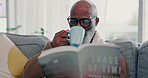 Tea, mature black man and reading book in home on living room sofa. Happy, novel and African person drink coffee in lounge to relax, study and knowledge of fantasy story in retirement hobby in house