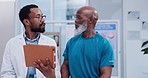 Tablet, consultation and senior man with doctor in a clinic for healthcare, wellness or recovery. Medical, digital technology and elderly African male patient talking to a chiropractor in a hospital.