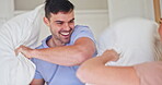 Smile, morning and pillow fight and a couple in bed together, having fun while playing a game in the morning, Love, energy or excited with a crazy man and woman in the bedroom of their apartment