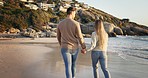 Couple, walking on beach sand and holding hands, travel and back view with love, bonding on romantic date outdoor. Man, woman on an adventure, journey and healthy relationship, freedom and ocean