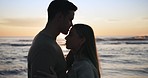 Sunset, beach and couple hug, kiss and share moment at the ocean for bond, freedom or travel. Sunrise, love and silhouette of man with woman embrace at sea with lens flare, care or romance in nature