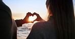 Silhouette, couple and heart hands, sunset at beach and love for bonding, romantic date outdoor with commitment. Man, woman and healthy relationship with adventure, support, ocean and trust with care