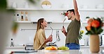 Dancing, utensils and couple singing in the kitchen for bonding, having fun or happiness. Smile, music and young man and woman doing karaoke together to playlist, radio or album at a modern apartment