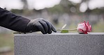 Funeral, cemetery and person with rose on tombstone for remembrance, ceremony and memorial service. Depression, sadness and hands with flower on gravestone for mourning, grief and loss in graveyard