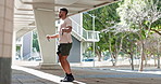Man, skipping rope and exercise outdoor in city for a workout, jump or training. Athlete person outdoor on urban street for cardio, fitness and energy for body wellness and health motivation