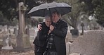 Support, death or old couple in cemetery for funeral, service or burial for repsect in Christian religion. Umbrella, depressed or sad senior people hug for comfort in graveyard crying in mourning