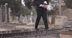 Funeral, walking in cemetery and man with flower for remembrance, burial ceremony and memorial service. Depression, death and sad person with rose for mourning, grief or loss in graveyard for respect