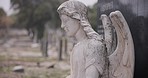 Angel statue, burial and tombstone in cemetery for death ceremony, funeral ritual and memorial. Religion, monument and resting place of departed for mourning, loss and remembrance of dead by church