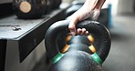 Weights, closeup and hand at the gym for fitness, exercise or training for muscle. Wellness, sports and a person, athlete or bodybuilder with a kettlebell at a club for cardio, power or strong