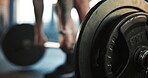 Closeup, barbell and athlete in gym for exercise, training challenge or workout in fitness club. Deadlift, strong bodybuilder and lifting heavy iron weights on ground for performance, action or power