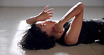 Performance, woman and lying on floor for dance in creative art studio with emotion and passion. African contemporary dancer practice for theater, sports and freedom with hands, exercise and talent