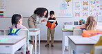 Teacher, child and reading a book in class for learning, development and communication. A boy kid or student and woman teaching language, support and assessment in elementary classroom at school