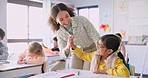 Teacher woman, high five girl and classroom with achievement, success and mentorship for learning. Education, development and students with goals, knowledge and books with celebration at school desk