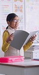 Child, paper reading and classroom with girl speaker, book and education at a school. Students, learning and notebook with development, knowledge and study with story discussion of youth assessment