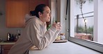 Woman, coffee cup and thinking by kitchen window, home and smile for happy memory, vision or nostalgia. Girl, drink and ideas with matcha, tea or espresso to relax, peace and mental health in house