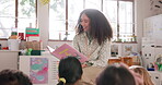 School, kids or teacher reading a book for learning, education or storytelling in kindergarten. Group, child development or woman teaching children students fun fantasy stories in classroom together