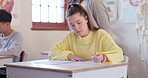 Education, exam and a student girl writing in class during a test or assessment learning or development. School, kids and female child at a classroom desk for academic study or scholarship assignment