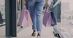 Shopping bags, walking and legs of woman in store, shop and travel commute to luxury fashion mall. Back, hands and gift of customer in boutique, retail market and sales discount on clothes of person