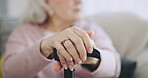 Cane, hands and elderly woman in home on living room sofa in retirement house. Walking stick, lounge and senior person with a disability on couch, closeup and crutch for support, balance or mobility