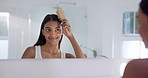 Skincare, bathroom and woman with brush for haircare, beauty routine and facial glow in home. Getting ready, girl in mirror for morning brushing hair, cleaning and fresh face in reflection in house.