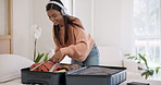 Headphones, happy and woman packing suitcase in home for travel, holiday journey or vacation preparation. Music, smile and Indian person with luggage in apartment, listening to radio sound and audio