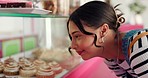 Bakery, window and woman with choice with cake, donuts and pastry options in restaurant and cafeteria. Breakfast, happy and person in coffee shop by glass for food, dessert products and sweets treat