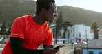 African man, phone and thinking with fitness, app or outdoor for reading, smile or laugh at comic meme on rooftop. Guy, smartphone and happy for contact, ideas and social media with training in metro