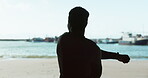 Sports, silhouette and a man stretching on the beach during fitness, exercise or training outdoor from behind. Health, wellness and workout in nature with a person by the ocean for a warm up