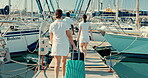 Boat port, suitcase and back of people walking to travel, vacation and summer trip at ocean. Luggage, pier and crew at ship dock, luxury holiday of tourist and outdoor on wood bridge at yacht at sea