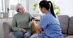 Blood pressure, test and caregiver help elderly woman on retirement with consultation on couch in home for support. Care, medical and nurse with advice for senior person in healthcare exam on sofa
