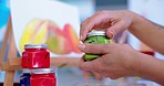 Paint, artist and hands of person with container for painting hobby, design and creation in workshop. Art, creative and closeup of painter with jars, color palette and canvas for creative drawing