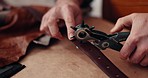 Hands, leather factory and scissors for belt, fabric and holes for manufacturing at desk in closeup. Entrepreneur, storage check or designer with creativity, fashion or cloth with quality assurance