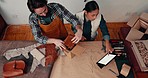 Manufacturing, leather workshop and industrial team packing an order in a cardboard box. Industry, collaboration and young man and woman with ecommerce small business for tanning process in office. 