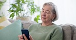 Phone, relax and senior woman on a sofa browsing on social media, mobile app or the internet. Technology, communication and elderly female person in retirement scroll on a cellphone in living room.