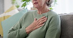 Hand, chest and a senior woman with heart disease on a sofa in the living room of her home closeup. Health, breathing and cardiac arrest with an elderly person alone in a house during retirement